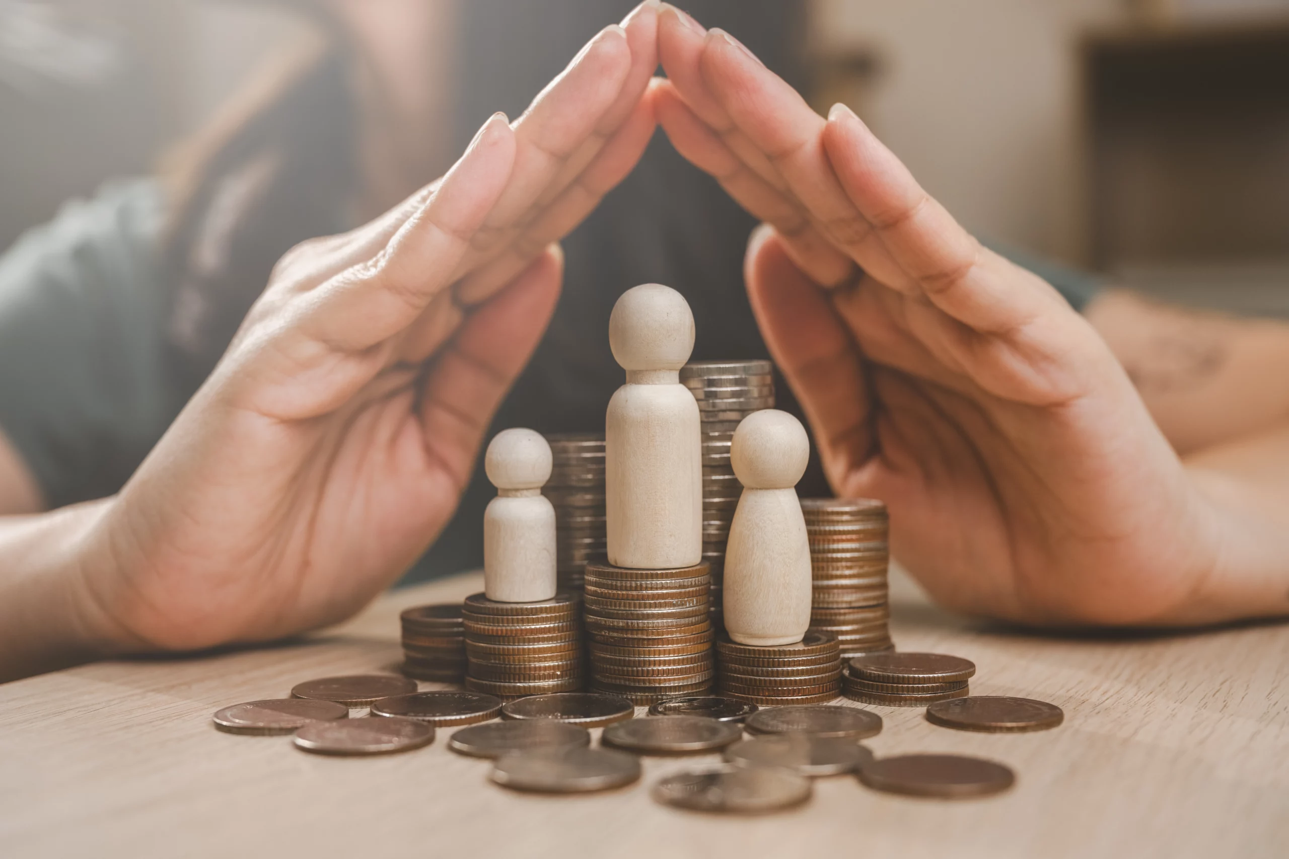 Hands over stacked coins and miniature people, symbolizing trust-based asset protection in Florida