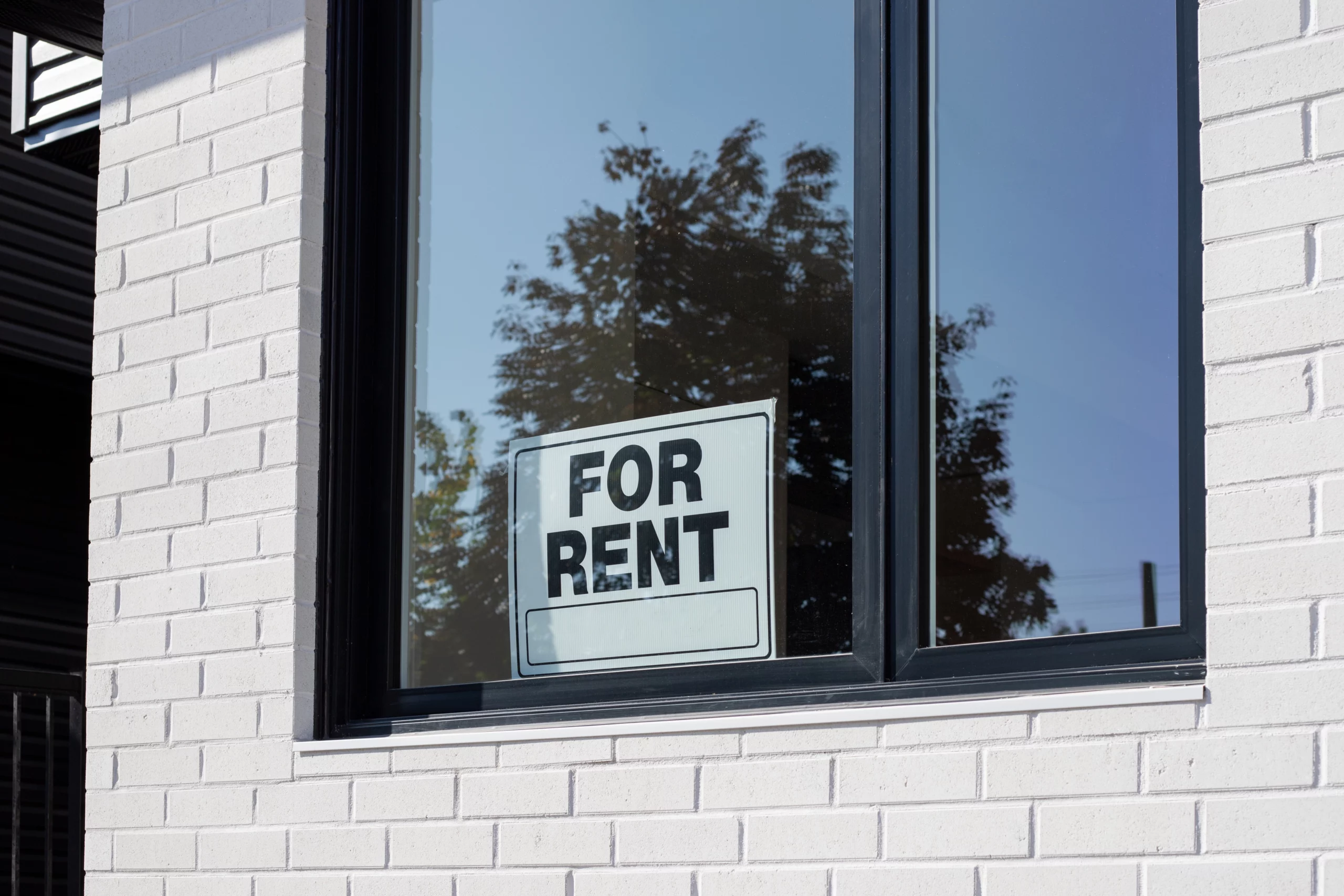For Rent sign in window of white brick building